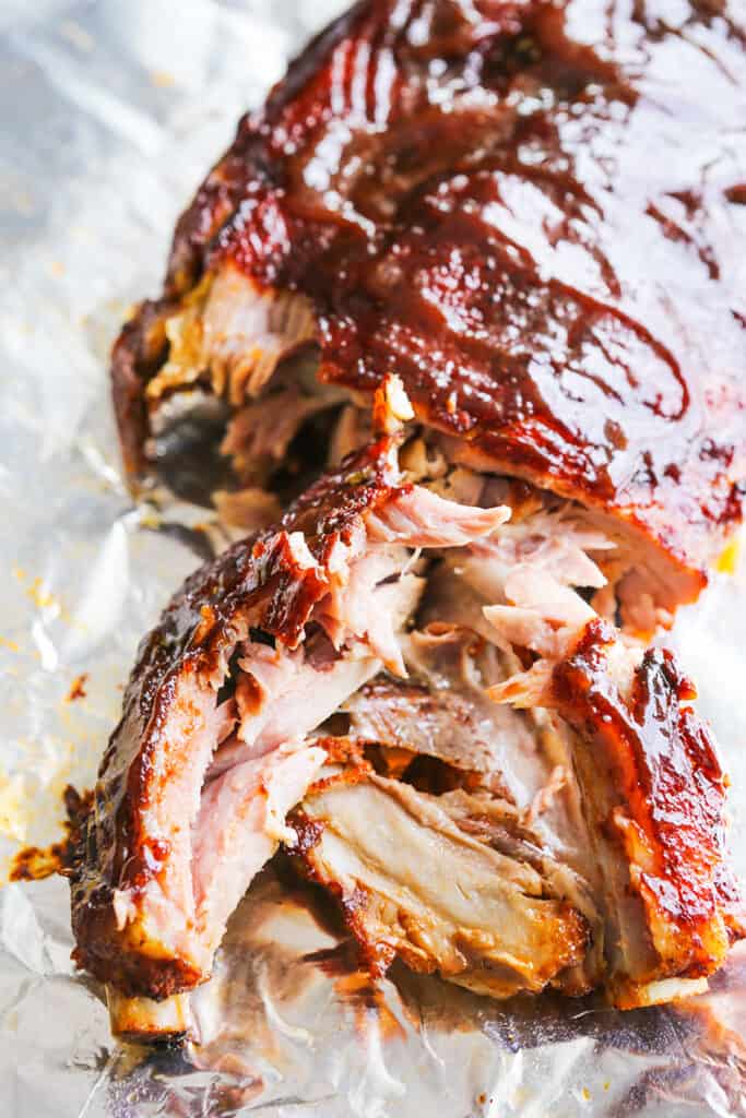 BBQ slathered instant pot ribs on a sheet of aluminum foil with a couple of ribs shredded off the bone. 