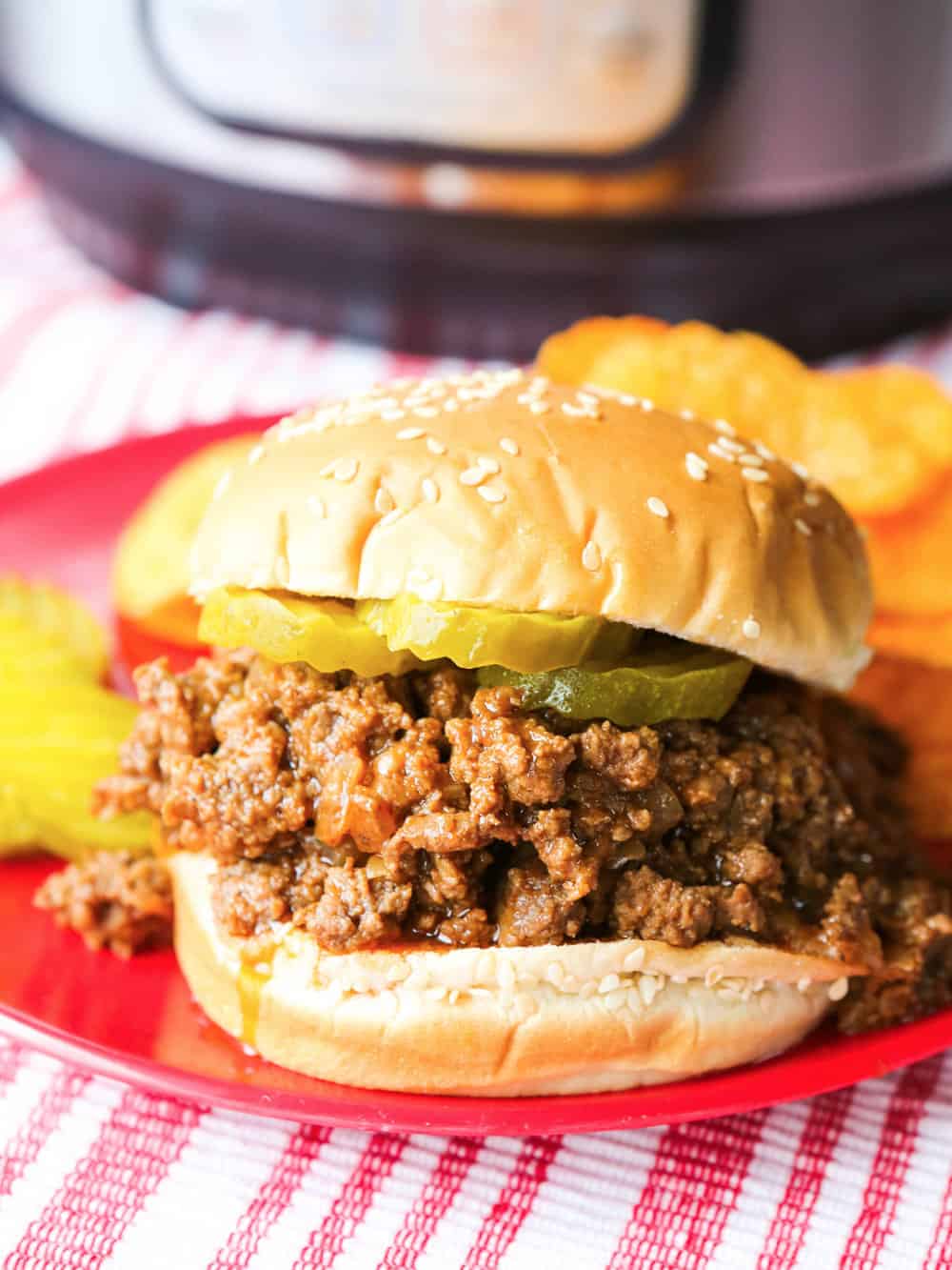 Sloppy joes on a sesame bun served on a plate. 