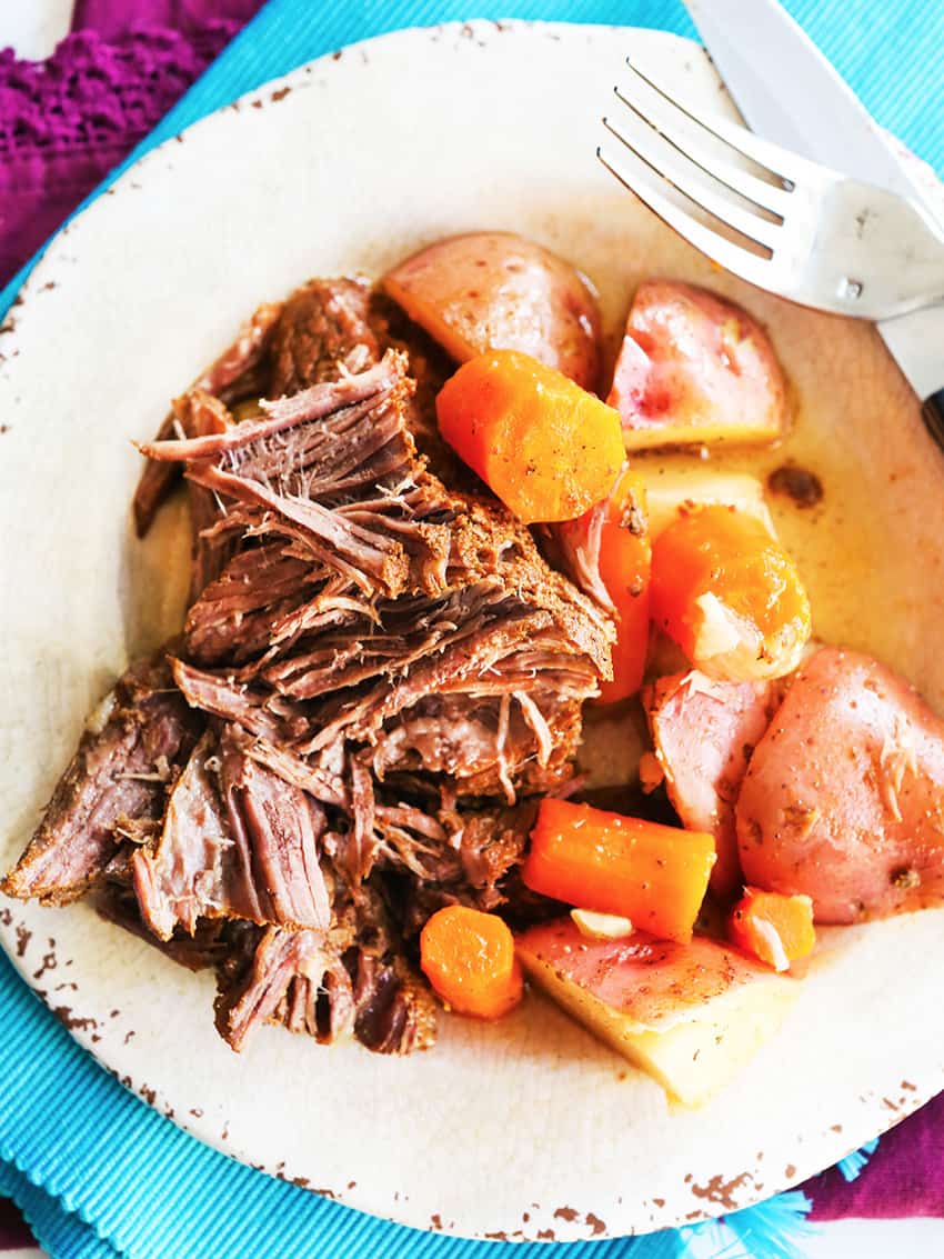 Instant pot pot roast on a plate with cooked carrots and potatoes. 