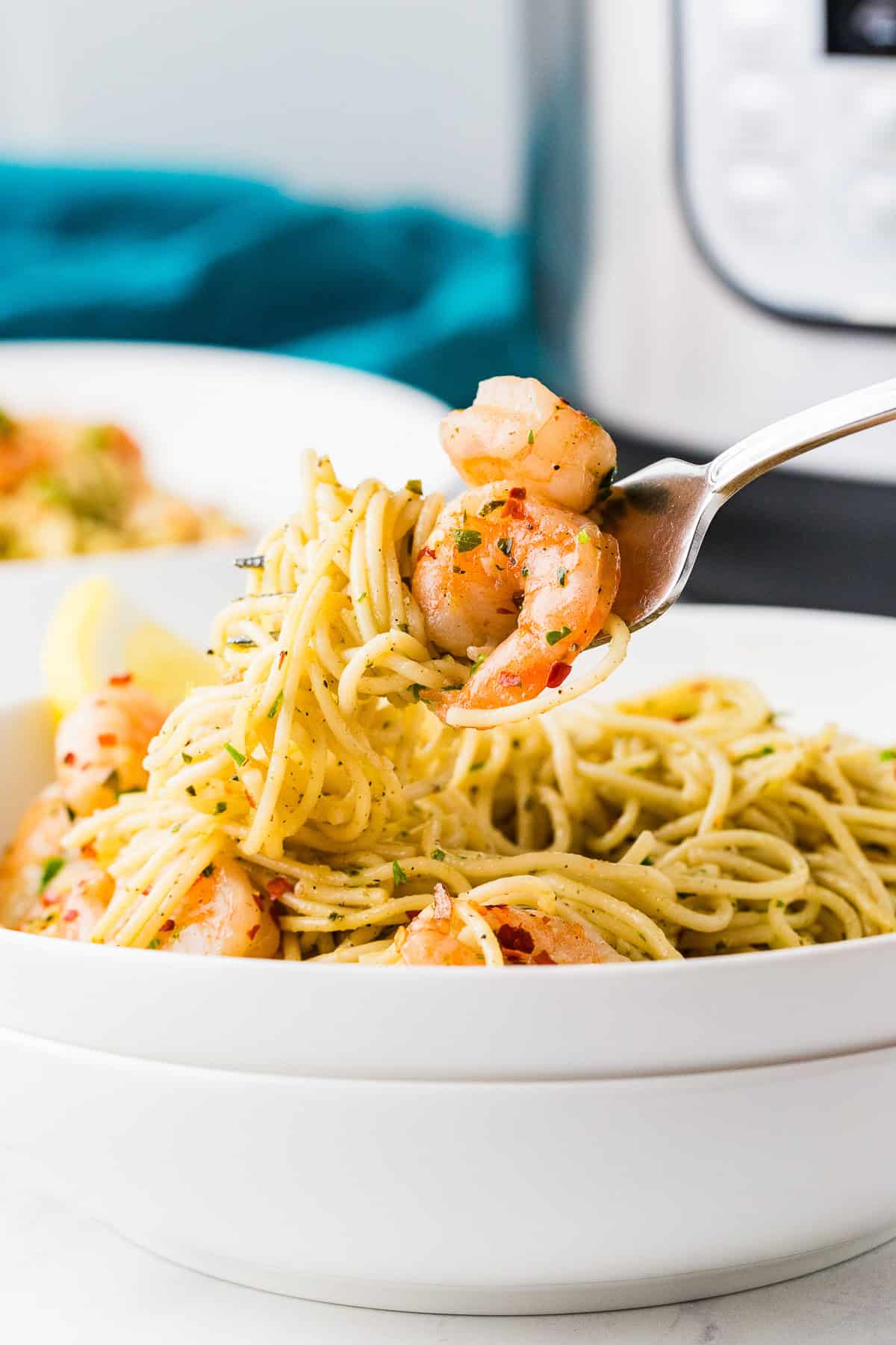 Fork pulling bite of shrimp and pasta from a plate.