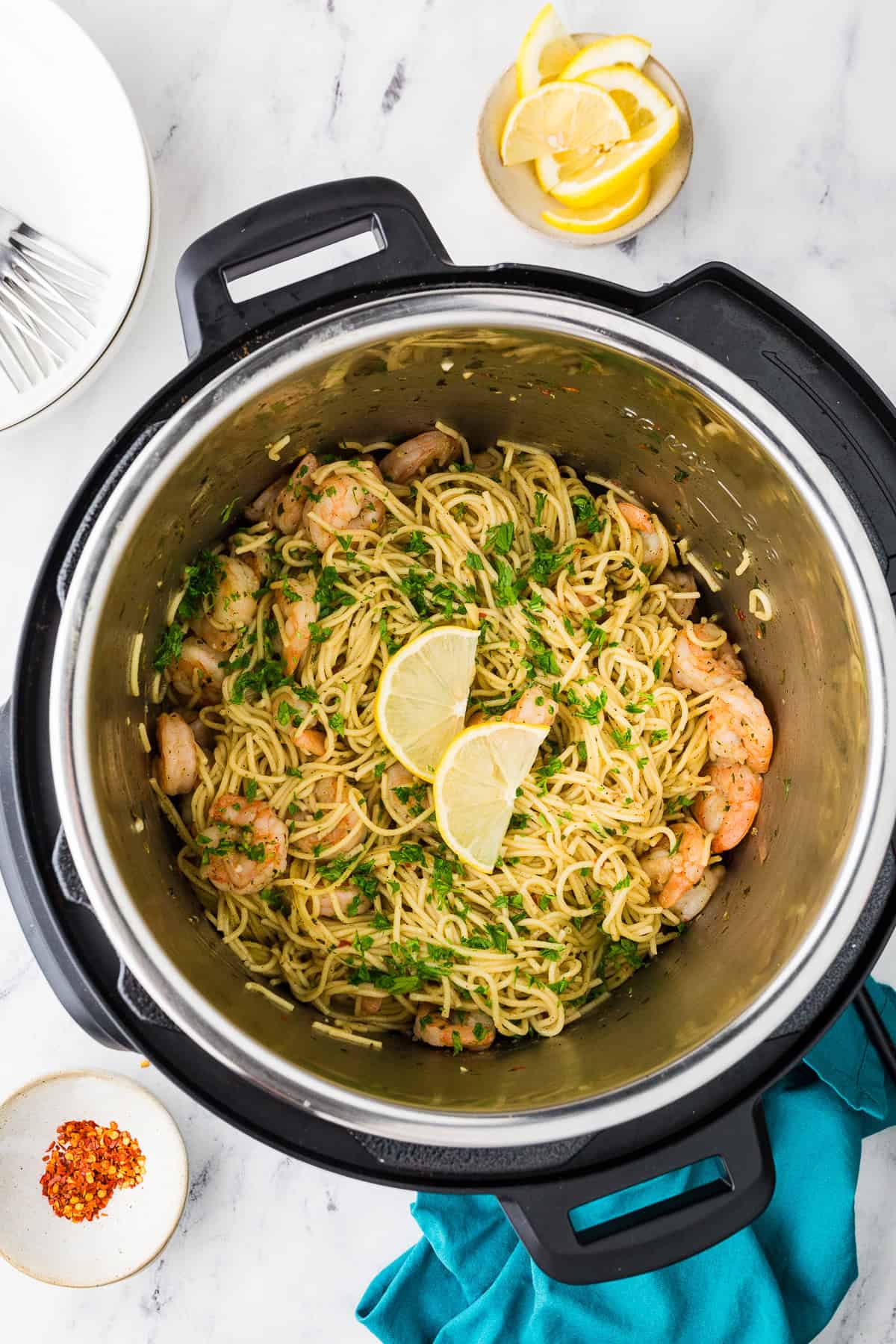 Top view of an Instant Pot filled with shrimp scampi, parsley and lemon wedges.
