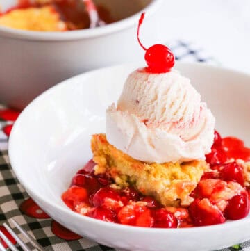 Cherry cobbler with vanilla ice cream and fresh cherries on top.