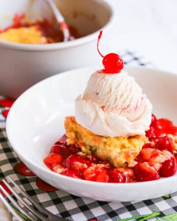 Cherry dump cake with vanilla ice cream and fresh cherries on top.