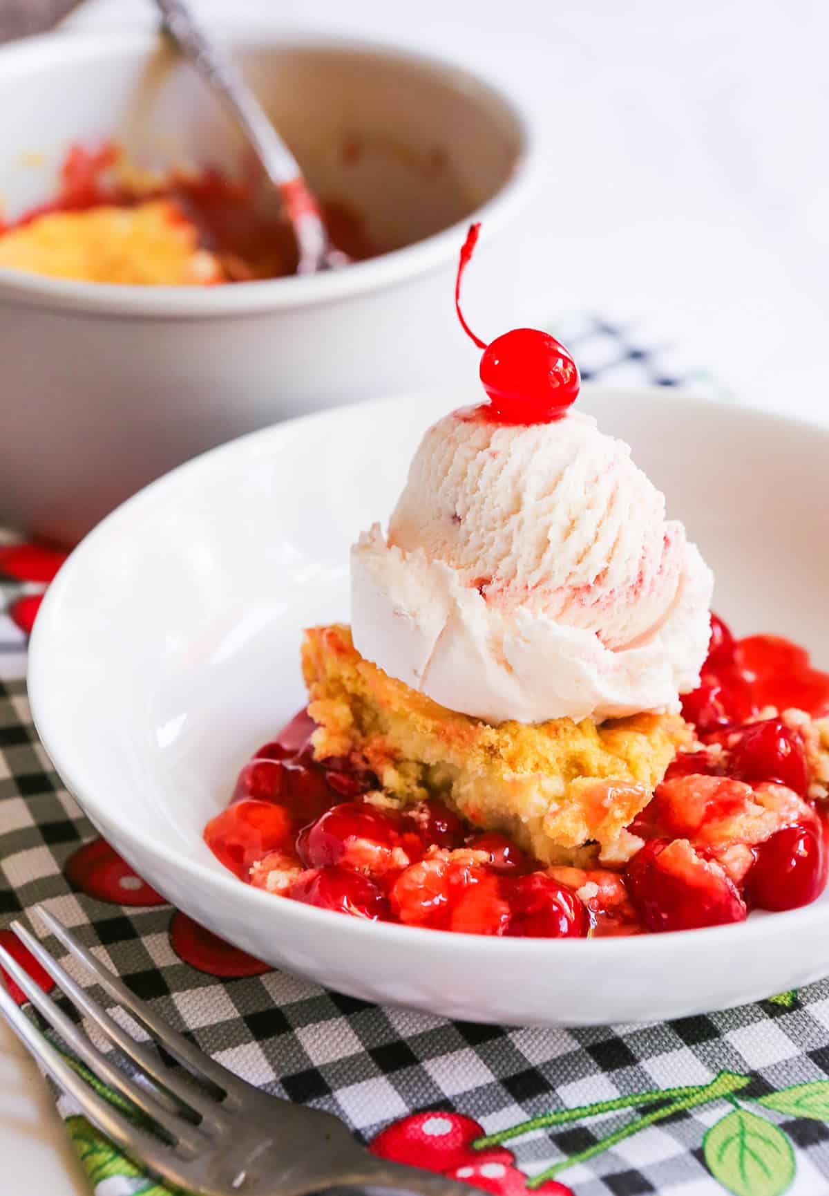 Cherry dump cake with vanilla ice cream and fresh cherries on top.