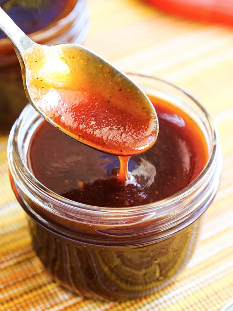 spoon dripping bbq sauce into a jar
