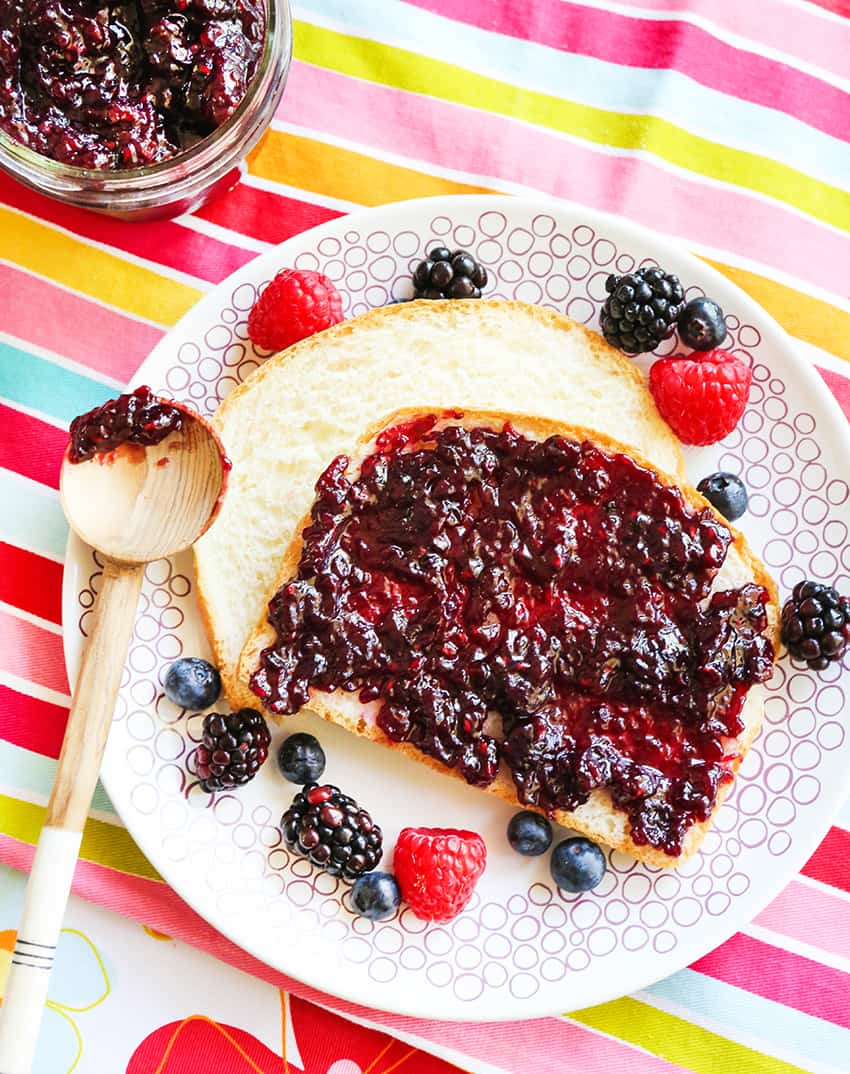 Berry jam on toast, next to a mason jar filled with jam.