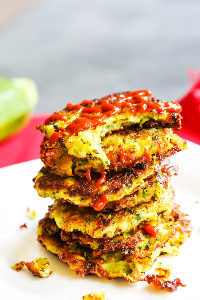 zucchini fritters topped on one another with ketchup drizzled on top