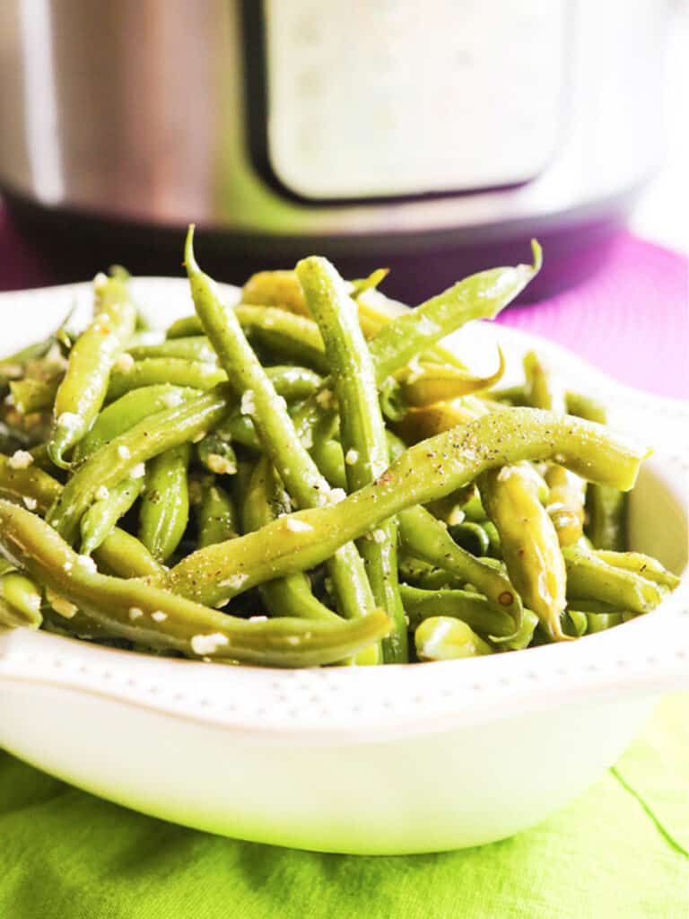 Serving bowl full of steamed green beans sprinkled with sea salt.