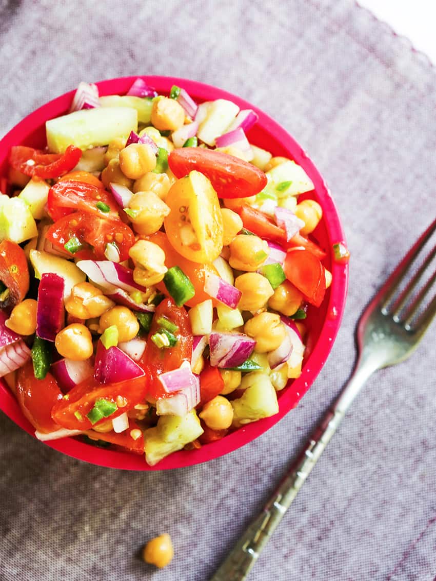 Bowl of spicy chickpea salad with a fork laying next to it. 