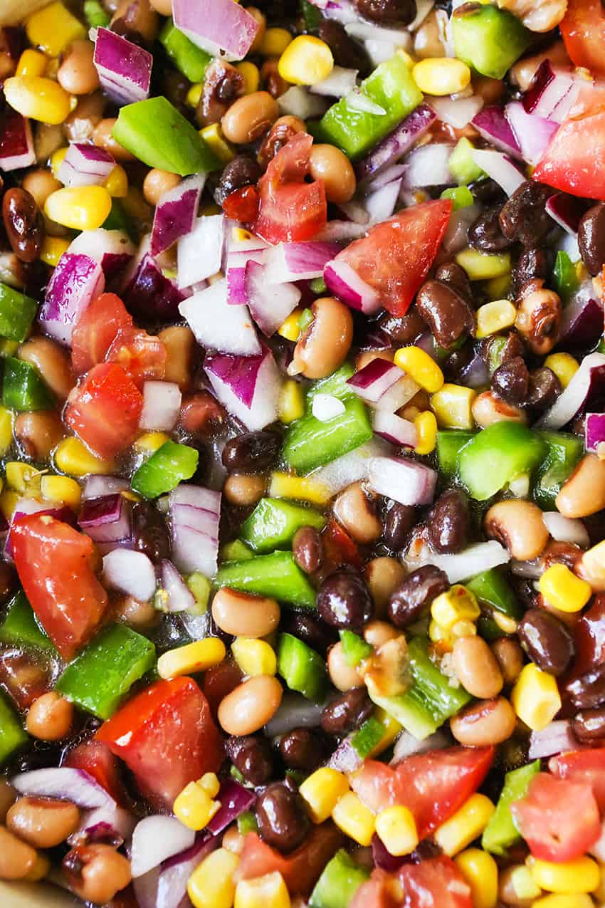 Close up of a salad with black-eyed peas, red onion, tomatoes, corn and green bell peppers.