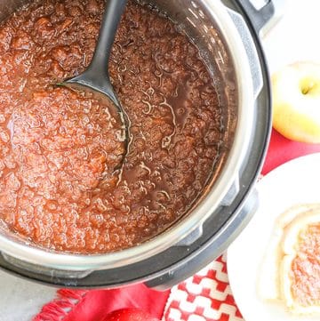 Cooked apple butter in an Instant Pot with a ladle, apples and bread on the side.