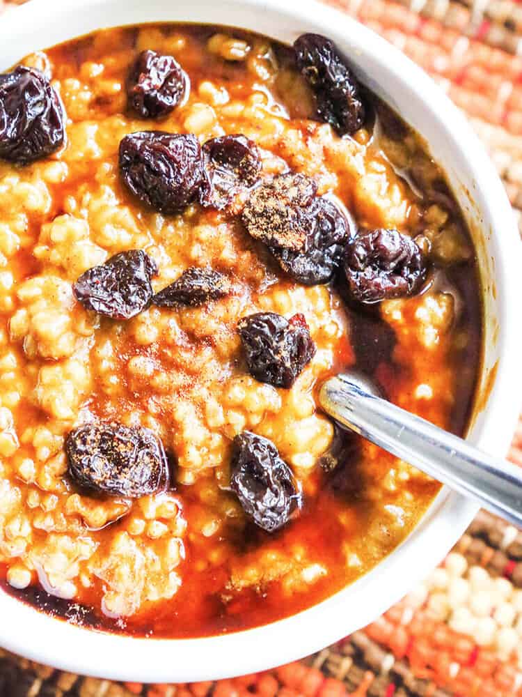 Bowl of instant pot oatmeal with pumpkin topped with raisins. 