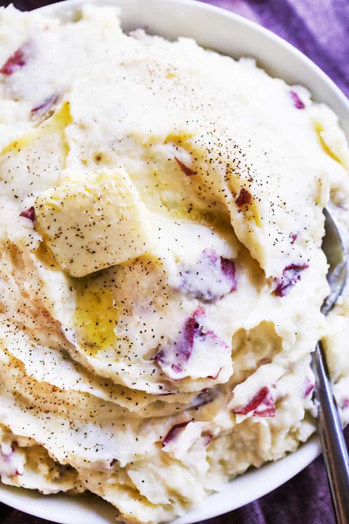 a serving bowl full of mom's mashed potatoes with a serving spoon tucked in