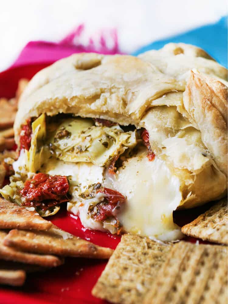 Baked brie with pesto, artichokes and sun-dried tomatoes.