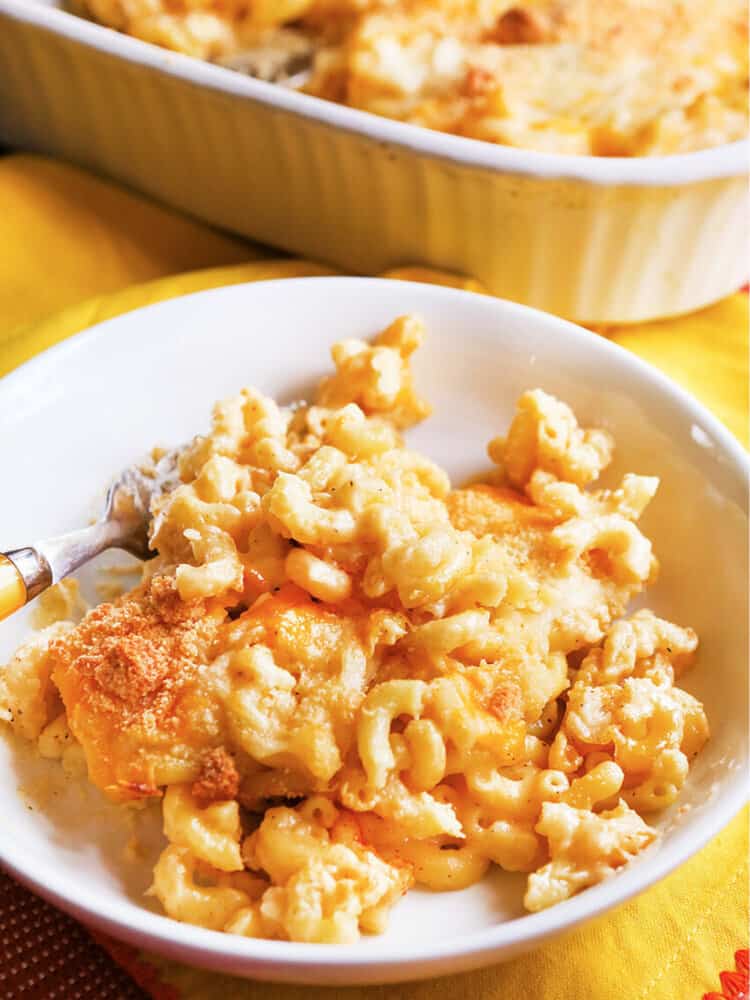 Bowl with baked mac and cheese with a crunchy top with a fork tucked inside. 