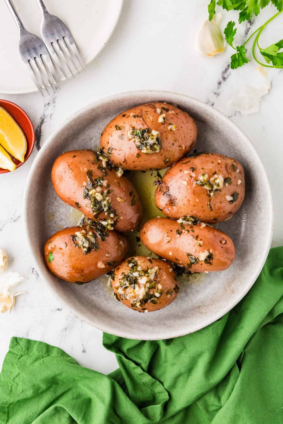 Top view of a serving bowl filled with potatoes, topped with a delicious parsley garlic butter topping.
