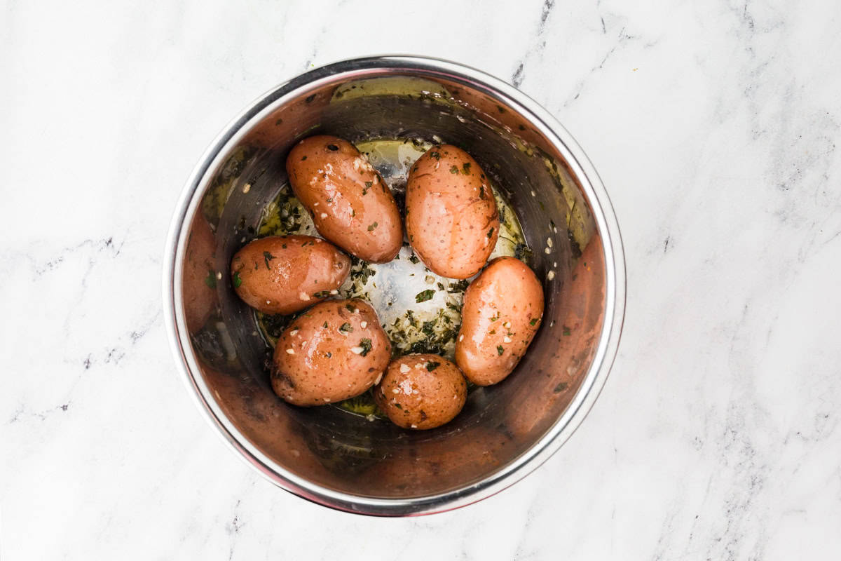 Cooked potatoes in a pot covered with parsley and melted butter.