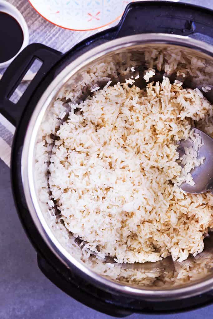 Top view of an instant pot filled with cooked rice and a spoon to serve with. 