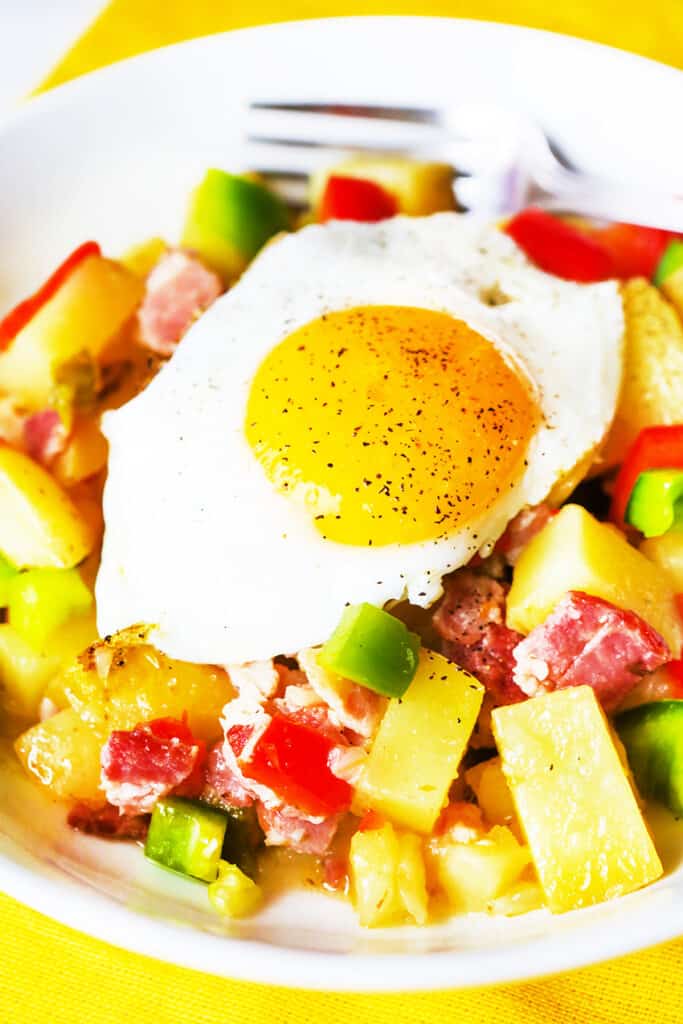 Breakfast potatoes with an egg cooked sunny side up on top. 