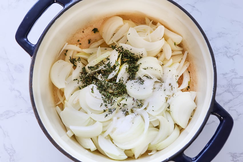 Sliced onions and thyme in Dutch oven ready for cooking