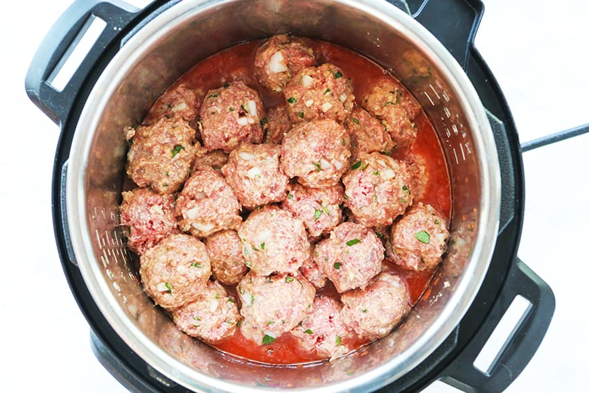 uncooked meatballs on top of sauce in Instant Pot