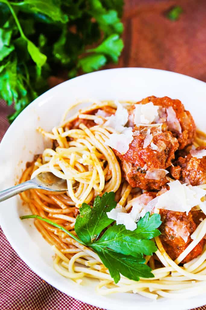 top view of plate of spaghetti with meatballs and shaved Parmesan.