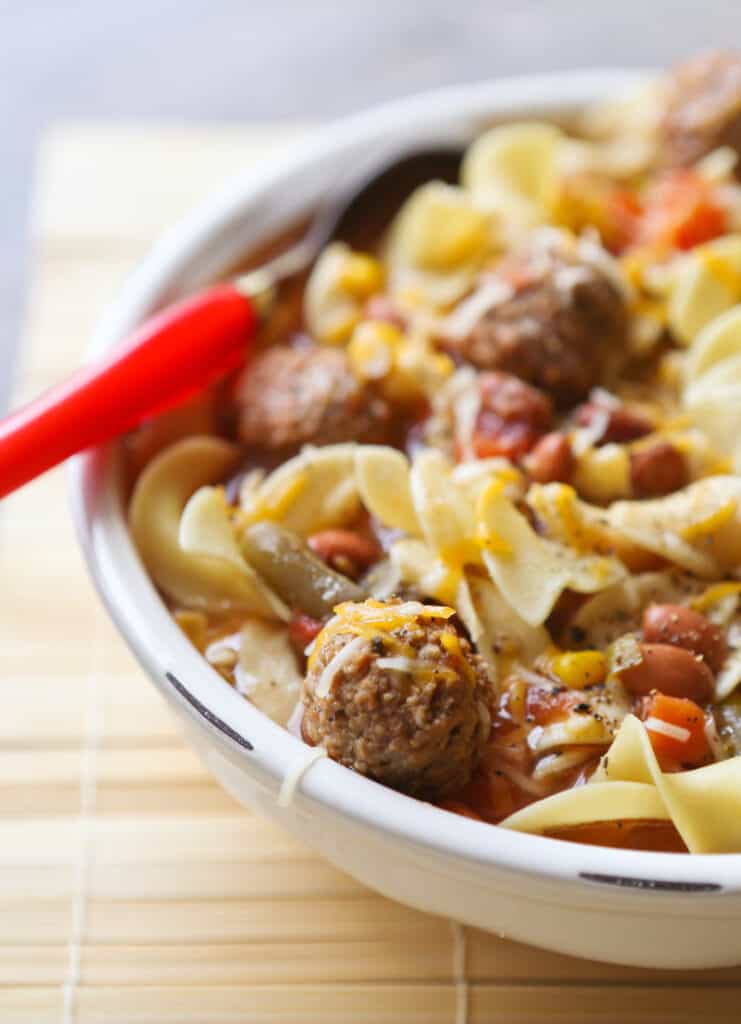 spoon digging into a bowl of meatball soup