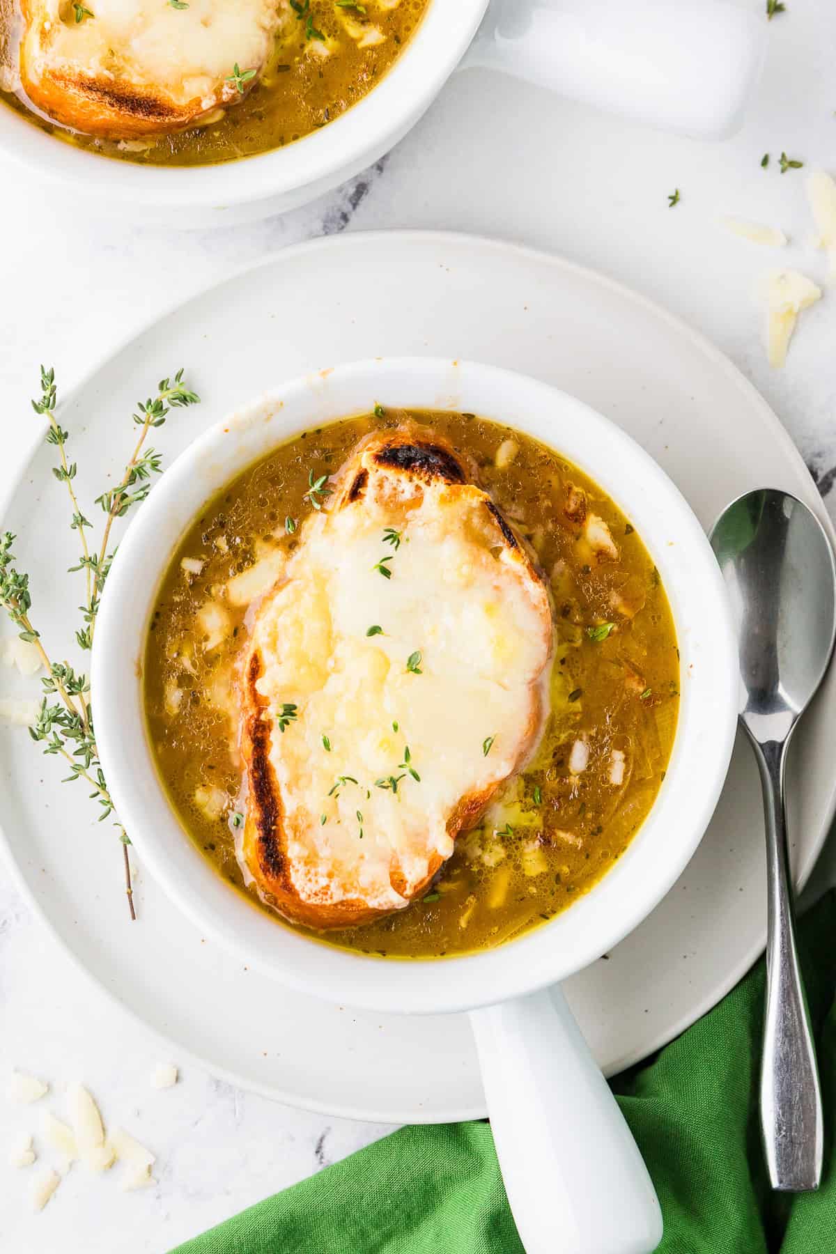 Top view of a delicious looking bowl of french onion soup topped with a cheesy toasted baguette.