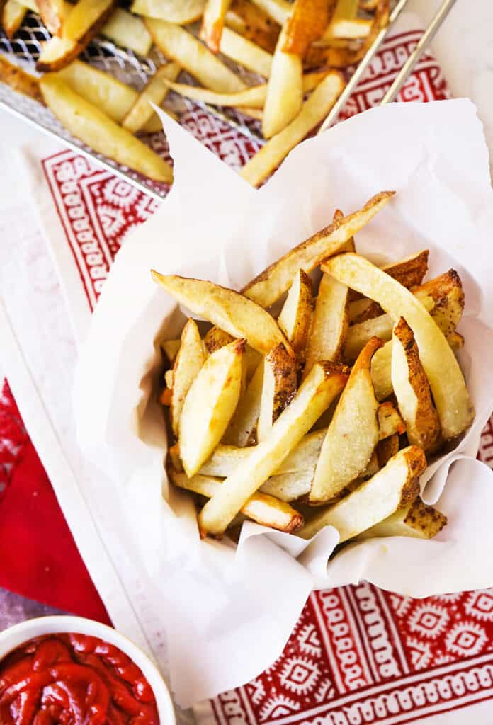 basket of french fries sitting next to small bowl of ketchup