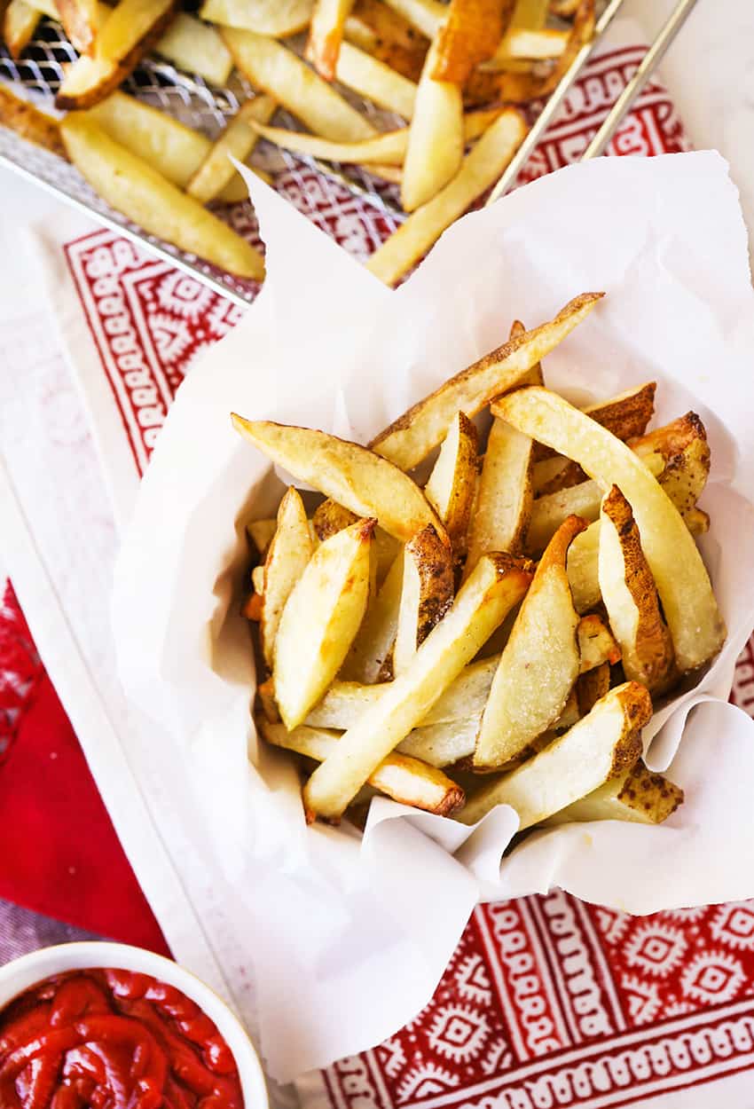 Perfectly cooked french fries in a bowl lined with parchment paper.