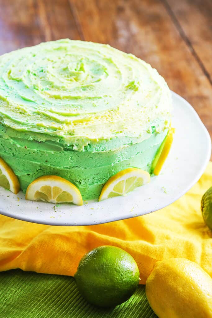 looking down on lemon lime layer cake with lemons and limes surrounding it