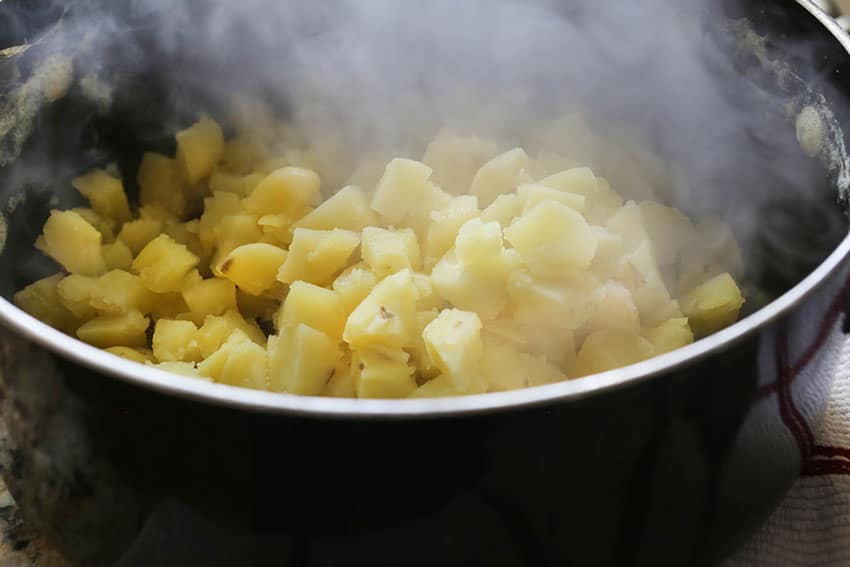 steaming pan of cubed cooked potatoes after being drained