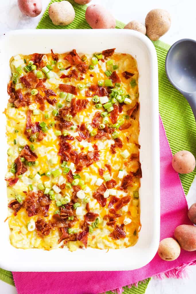 potato casserole in a baking pan topped with bacon and green onions