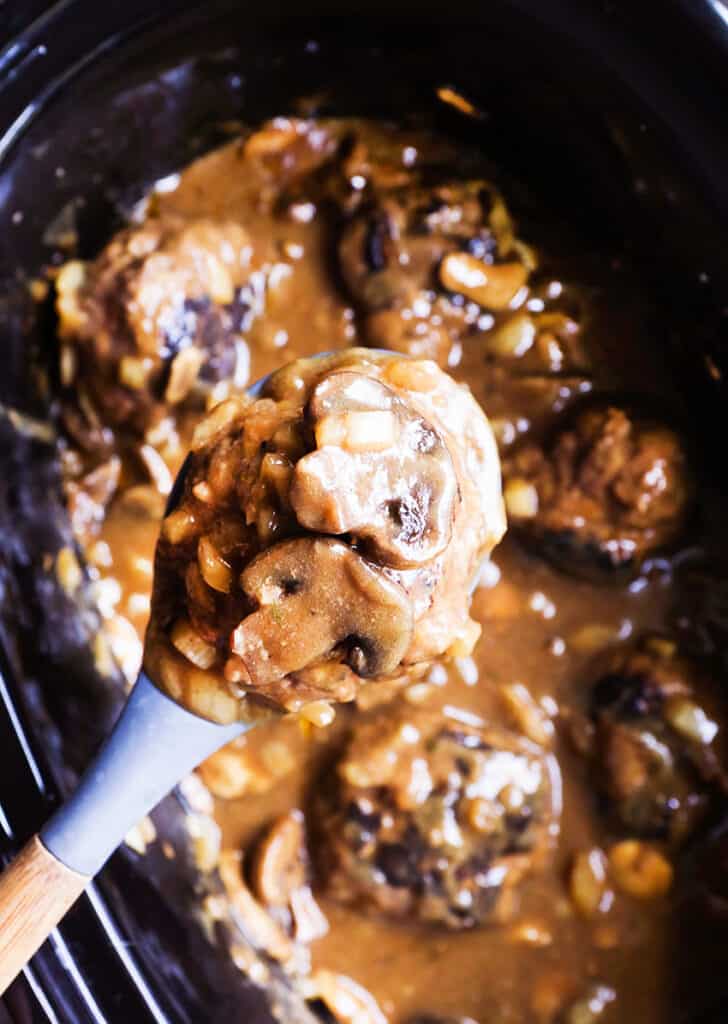 huge spoonful of salisbury steak with mushrooms hovering over crock pot.