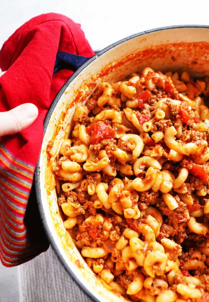 hand holding Dutch oven filled with cooked Goulash