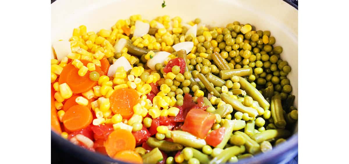 A bunch of canned vegetables emptied out into a Dutch oven.