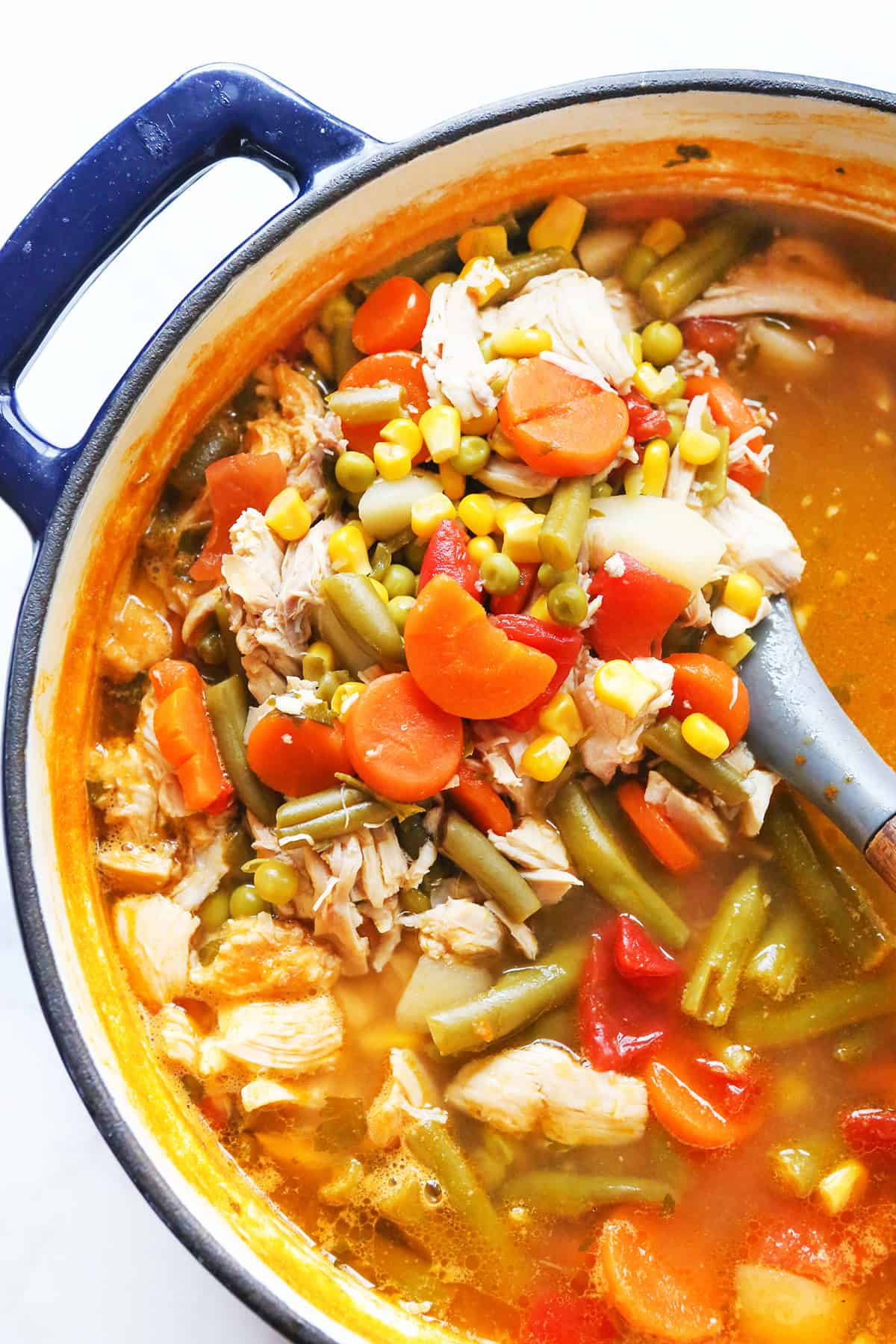 Top view of a Dutch oven filled with vegetables, chicken and a yummy looking soup mixture.