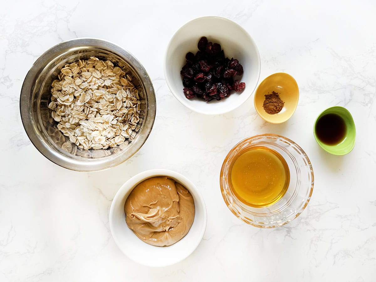 Ingredient for energy balls in individual bowls on a white counter.