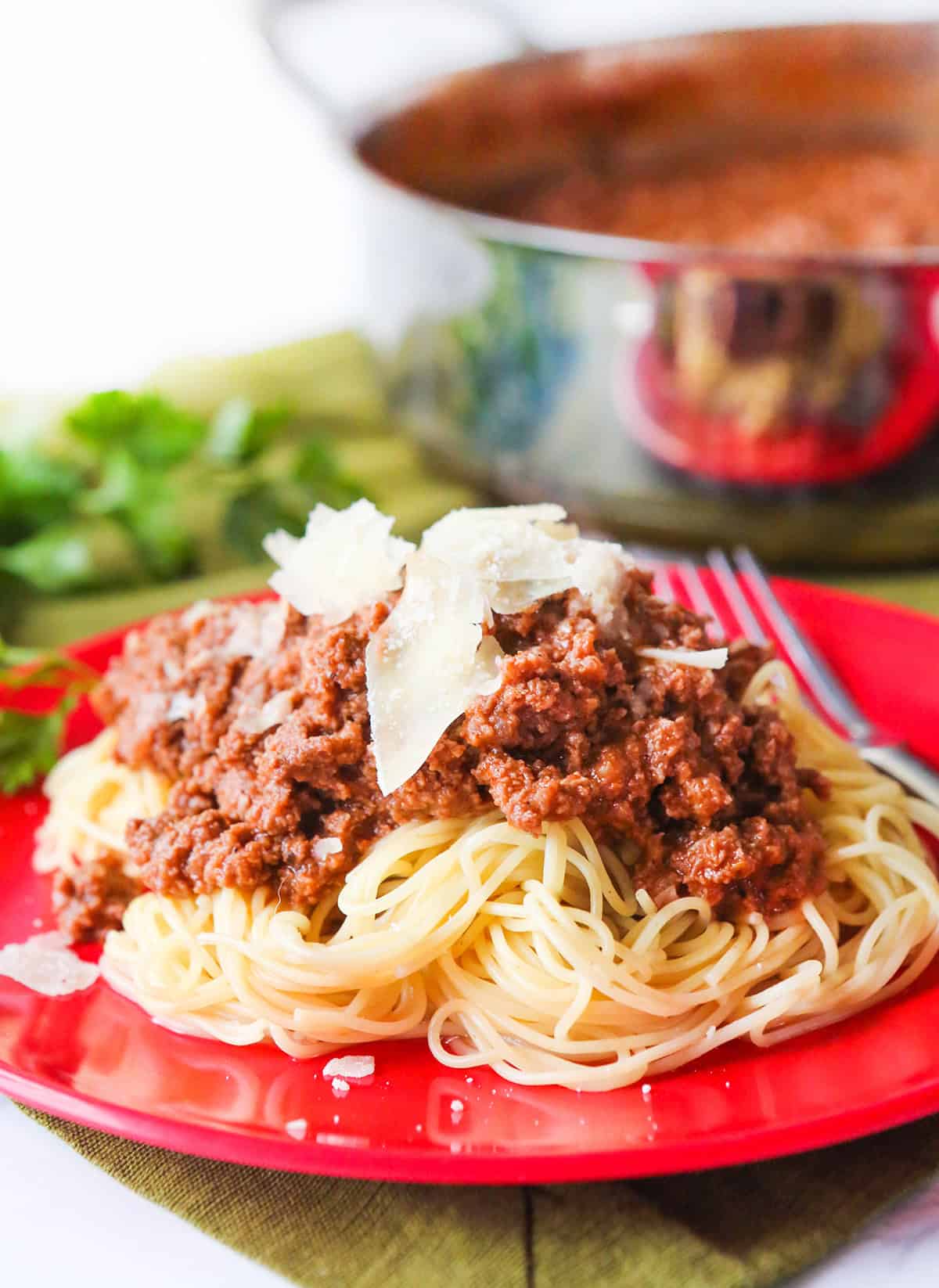 Plate of spaghetti with meat sauce and Parmesan cheese on top.