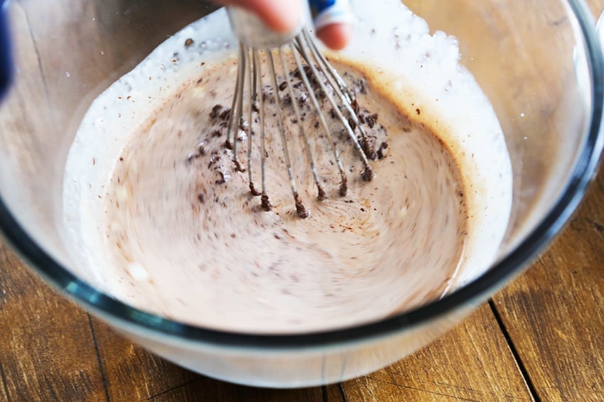 whisk in glass bowl combining chocolate and cream