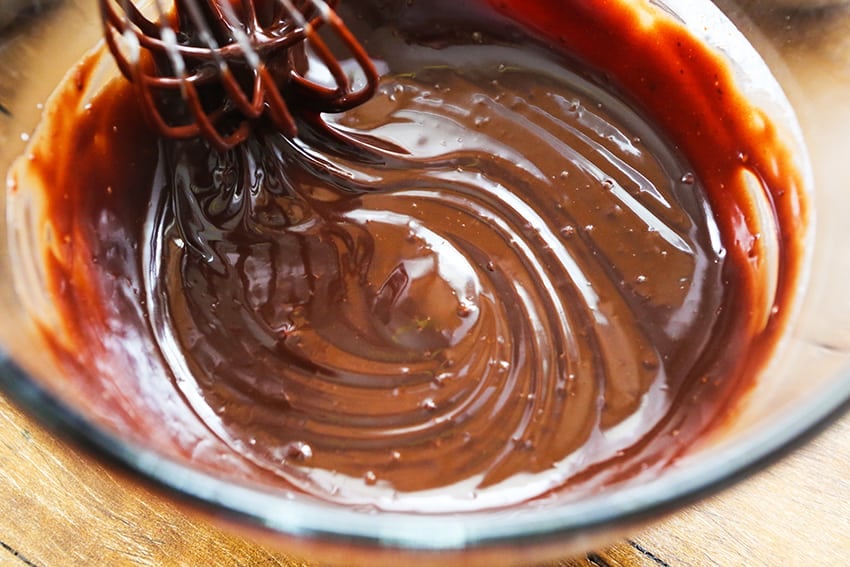 creamy chocolate ganache in a glass bowl with a whisk stirring
