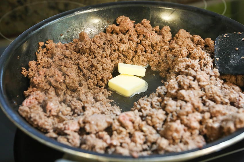 2 pats of butter in the center of ground beef in a skillet