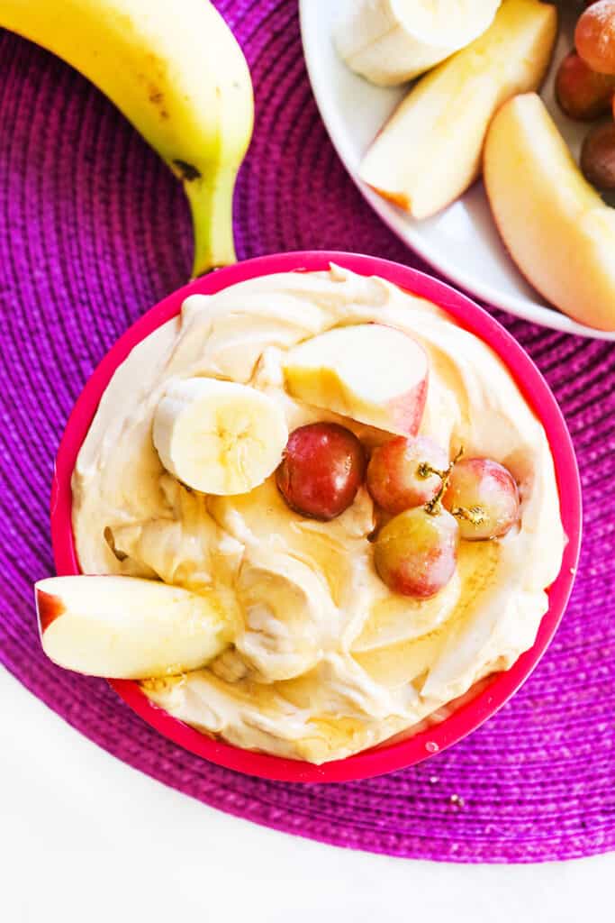 bowl of fruit dip with fruit inside and sitting next to platter of fresh fruit