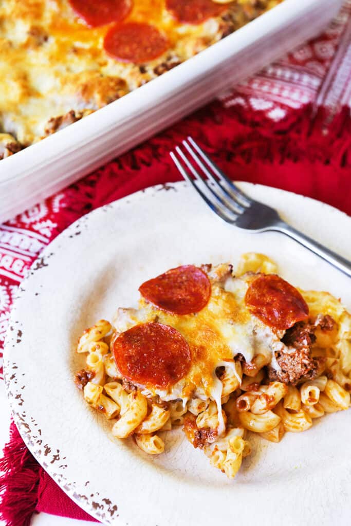 plate of cheesy, meaty pasta casserole sitting next to pan
