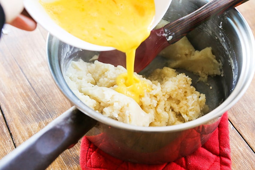 Egg mixture being poured into batter in a saucepan