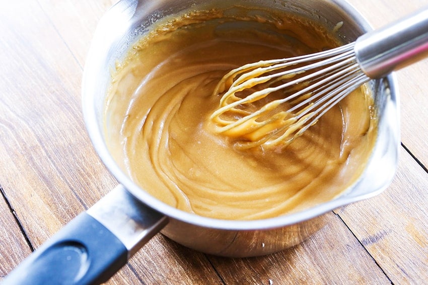 whisk resting in saucepan full of smooth caramel