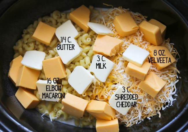 mac and cheese ingredients with text labels in a crockpot before cooking