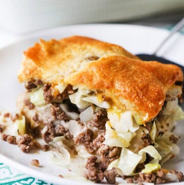 Slice of runza casserole with beef, cabbage, and golden crust on a white plate.