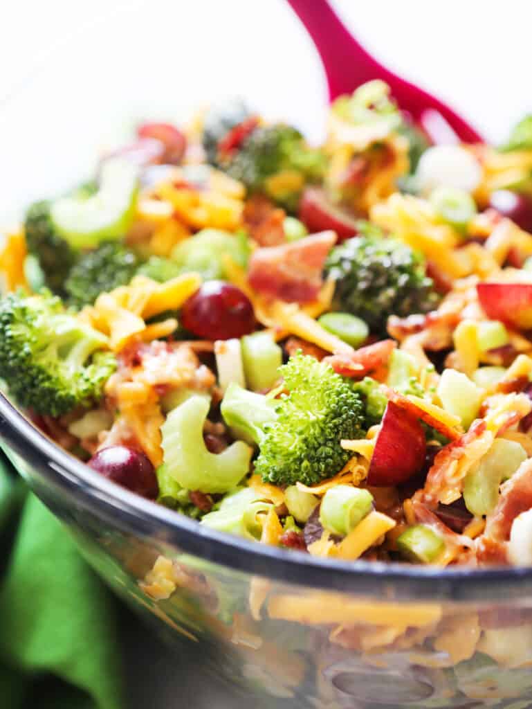 close up of bowl of broccoli salad with grapes, bacon pieces and celery