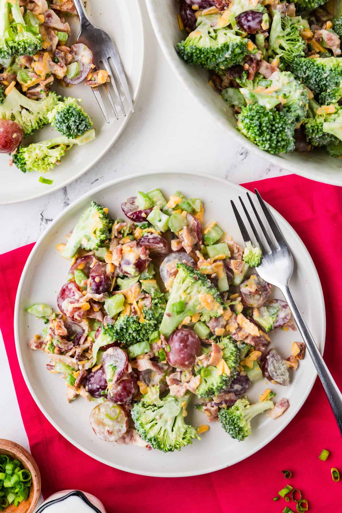 Top view of a plate of broccoli salad next to a bowl filled with the mixture.